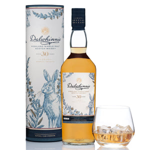 A bottle of Dalwhinnie 30 Year Old Special Release 2019 with box and a glass of whisky on the rocks against white background